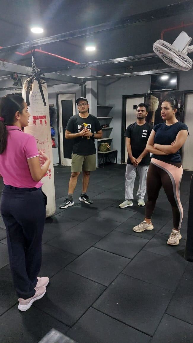 People engaging in a discussion inside a gym, surrounded by fitness equipment like punching bags and exercise mats at boxfit