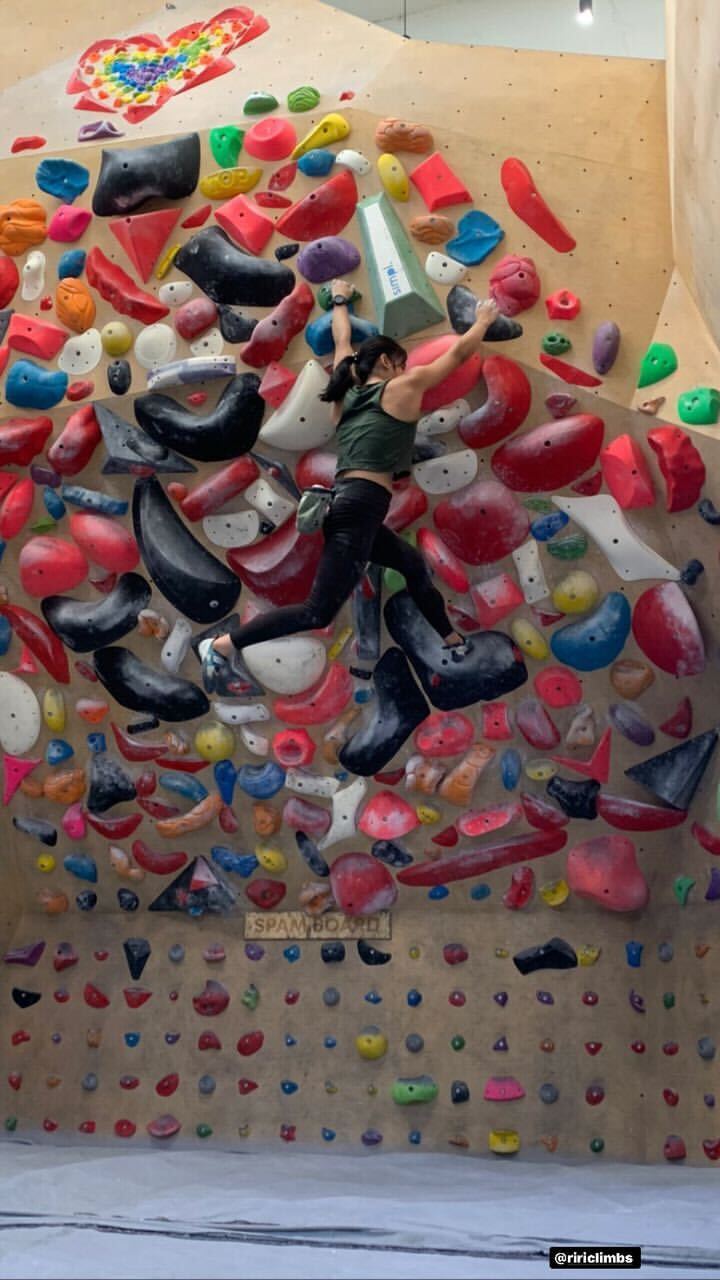 Female climber scaling a colorful indoor climbing wall with various grips at Boulder Blast competition by Savikalpa