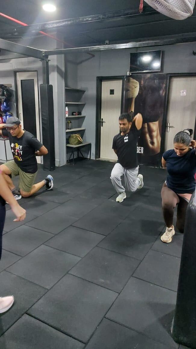 Fitness training session in a gym where participants, perform lunges and other exercises under the guidance of a trainer