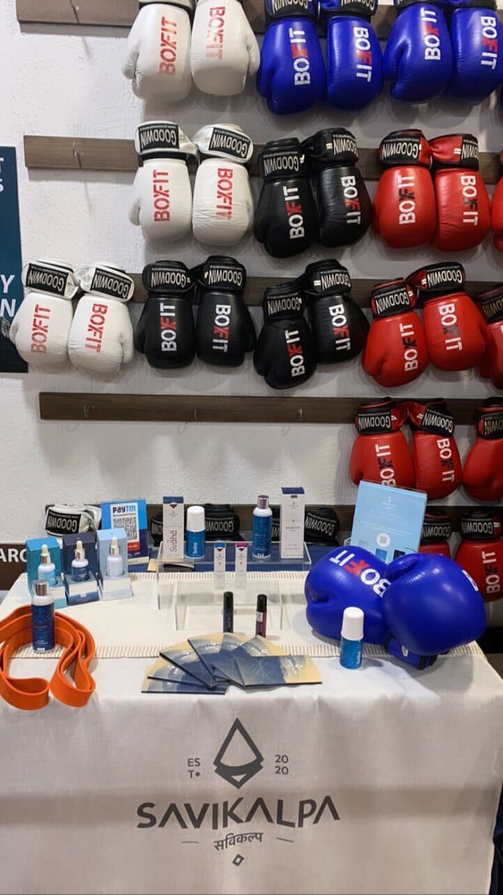 Exhibition booth at BoxFit gym with Savikalpa products arranged on a table, with boxing gloves in the background