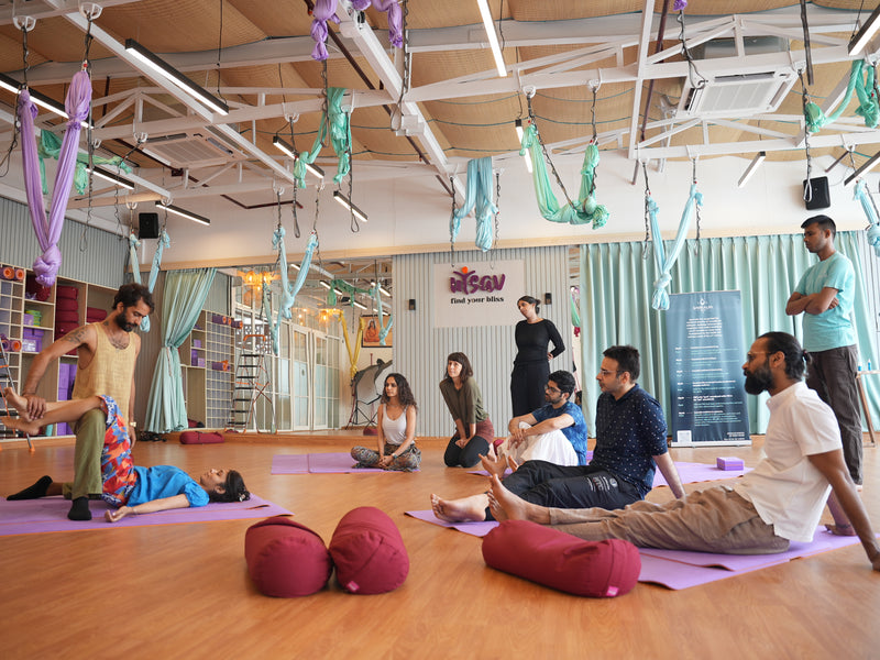 A Savikalpa bodywork and massage workshop in session with a diverse group of participants and instructors in a yoga studio