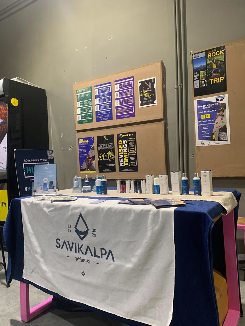 Event booth at all women climbing event, displaying Savikalpa products on a white branded tablecloth, and event pamphlets.