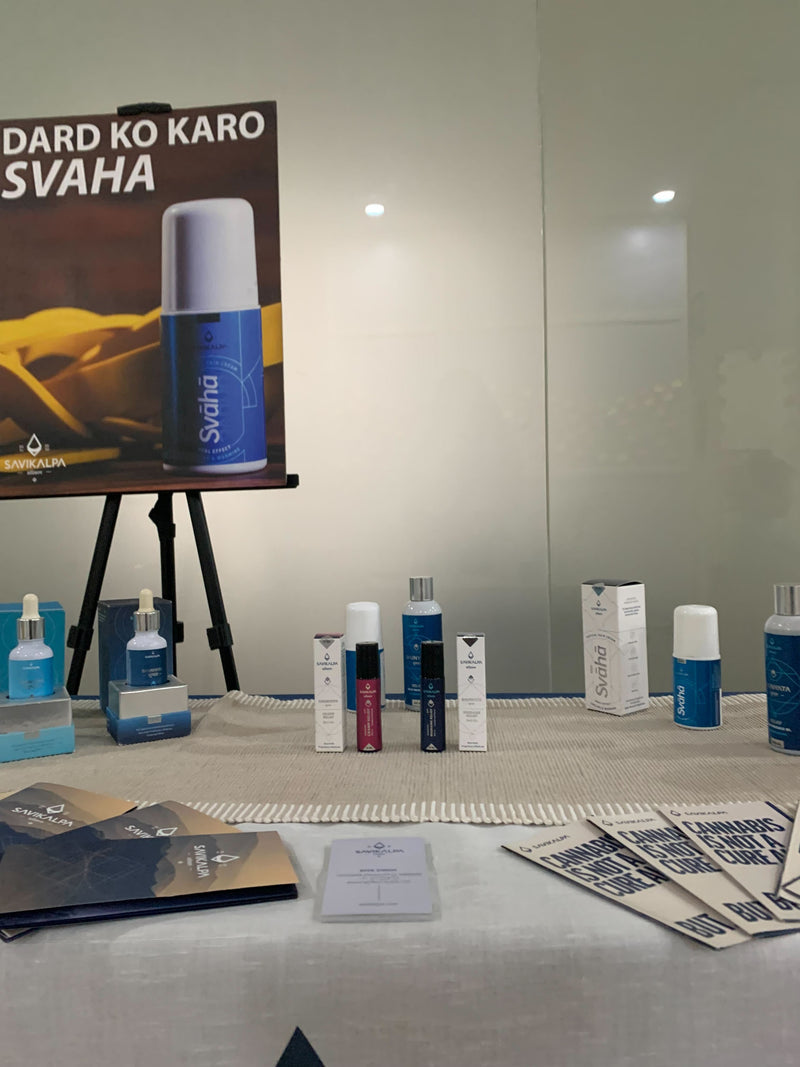 Close-up of products display on a table with a Savikalpa branded cloth at a workshop, featuring oils, cream & roll ons