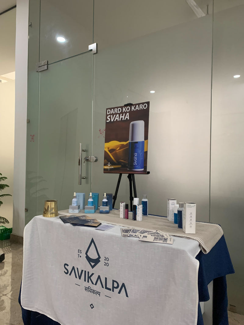 Products display on a table covered with a Savikalpa branded cloth at a workshop, featuring oils, cream & roll ons.