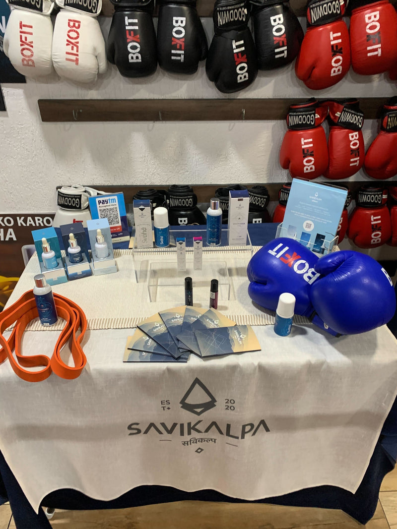 Promotion booth at BoxFit gym with Savikalpa products and flyers arranged on a table, with boxing gloves in the background