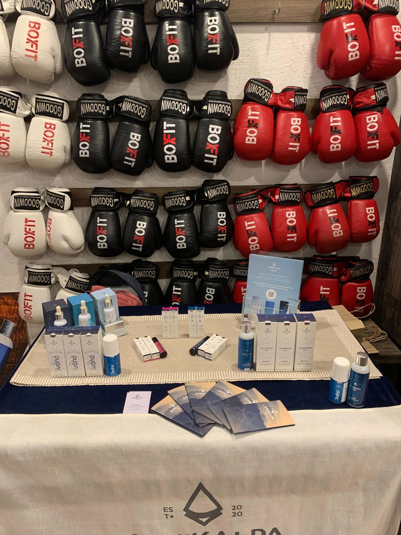 View of Savikalpa promotional booth at BoxFit gym featuring a range of products, promotional banners, and boxing gloves